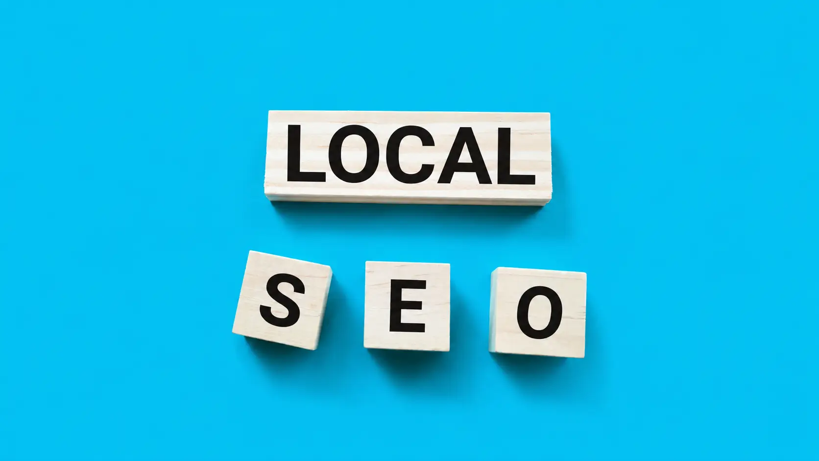 Τι είναι το local SEO: Απεικόνιση των λέξεων «LOCAL SEO» με ξύλινα γράμματα σε γαλάζιο φόντο, που συμβολίζει τη στρατηγική τοπικής βελτιστοποίησης στις μηχανές αναζήτησης.